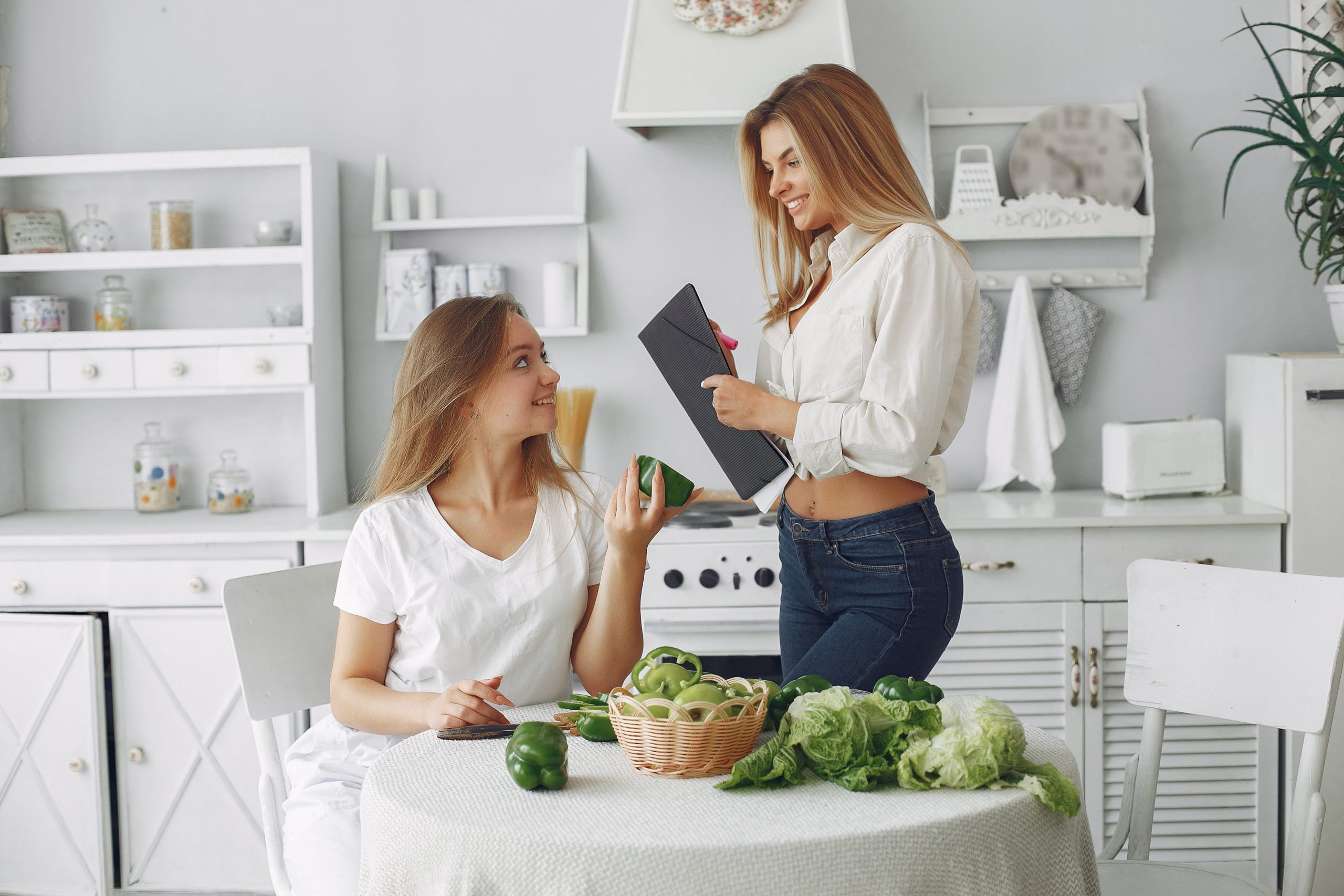 Beautiful and sporty girls in a kitchen with a vegetables