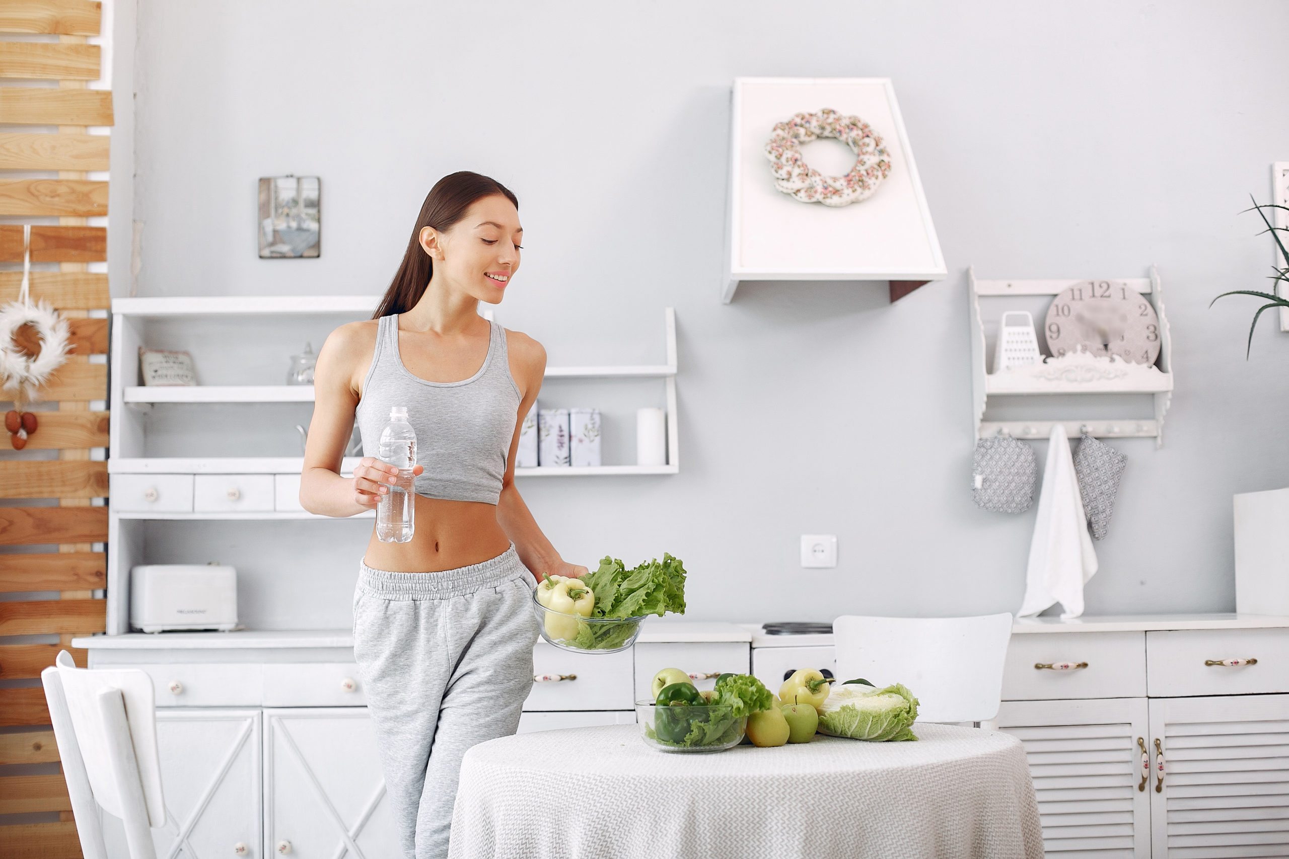 Beautiful and sporty girl in a kitchen with a vegetables